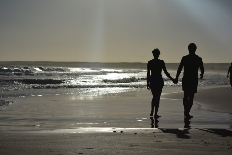浜辺で手を繋ぐカップル